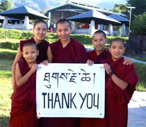 5 Tibetan Buddhist nuns hold a thank you sign in Tibetan and English