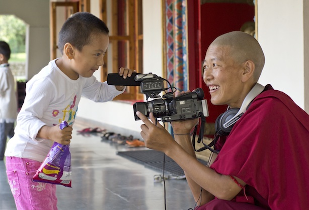 Tibetan Buddhist nun with video camera filming child