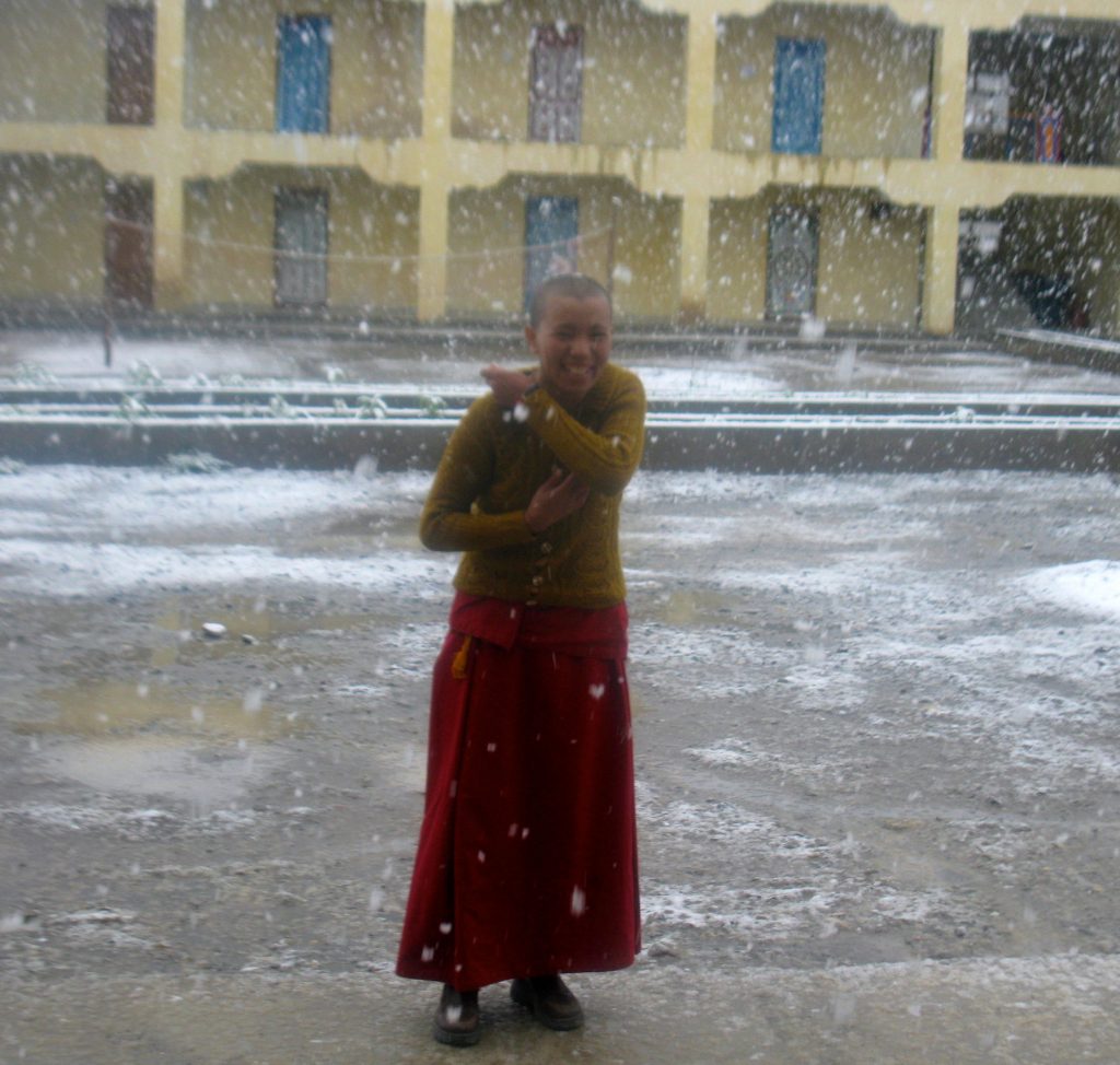 Tibetan Buddhist nun in snowfall at Sherab Choeling Nunnery