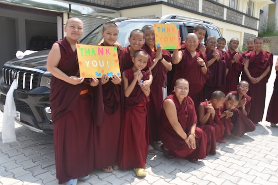 Tibetan Buddhist nuns from Dolma Ling Nunnery hold up thank-you signs to express gratitude for their new vehicle.