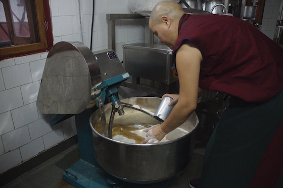 Tibetan Buddhist nun making dough with electric mixer