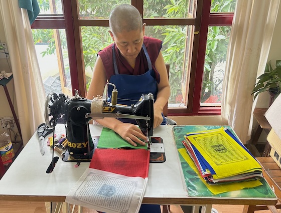 Tibetan Buddhist nun sewing Tibetan prayer flags
