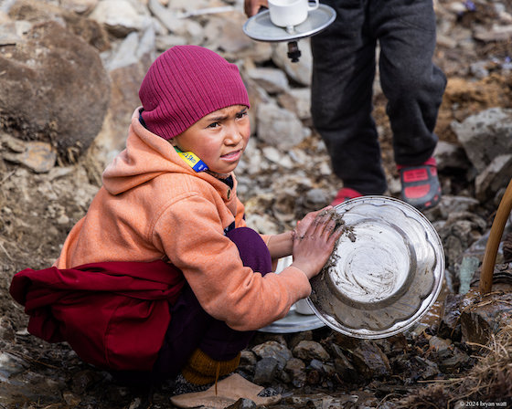Life at Dorjee Zong Nunnery. Young Tibetan Buddhist nun washes her dish outside in cold water